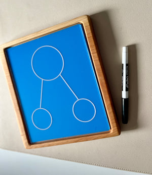 Rectangular wooden-framed blue board with three connected circles next to a black and white marker on beige surface