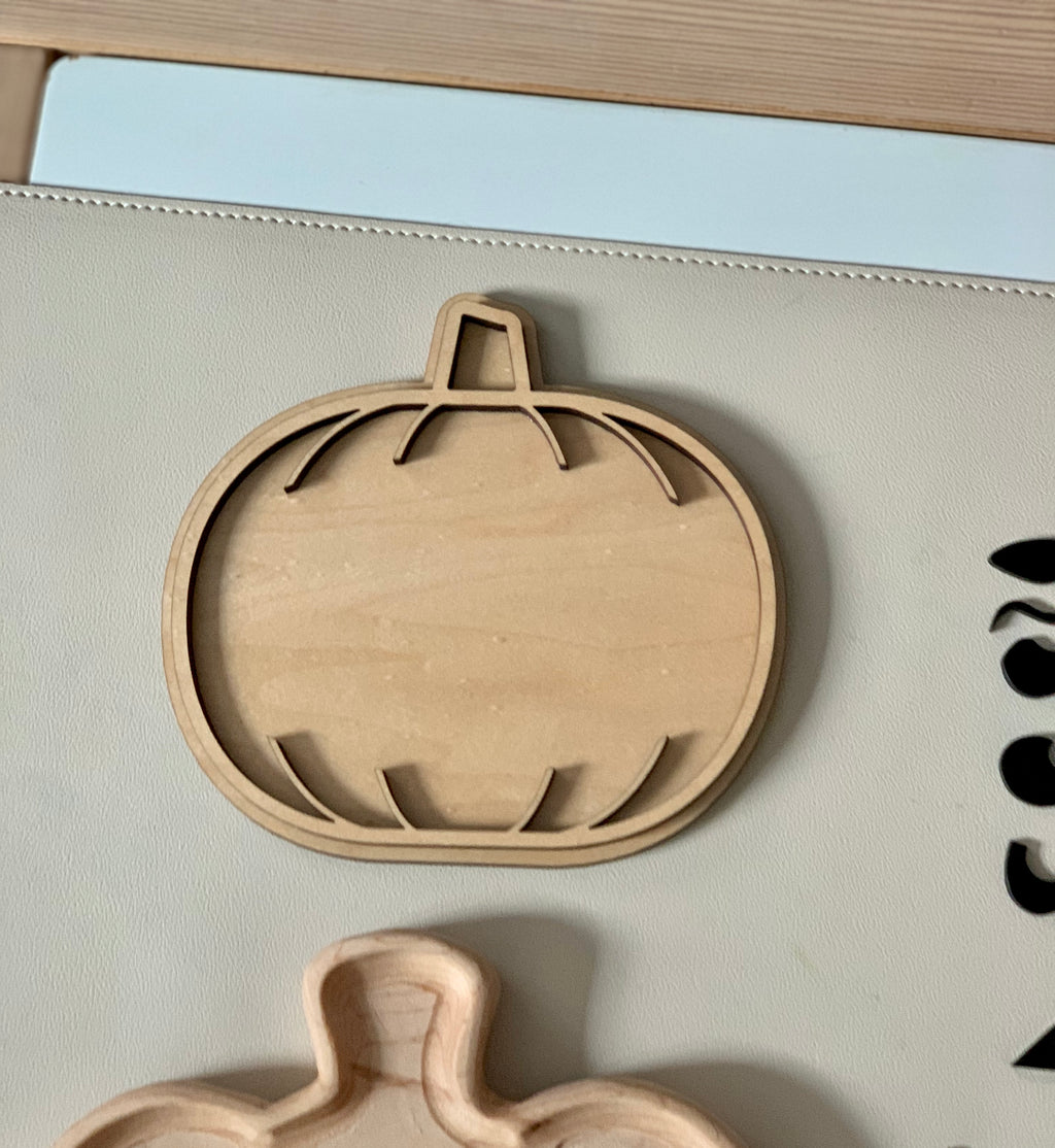 Laser cut wooden pumpkin-shaped sensory tray with carved grooves on light beige surface