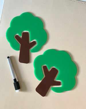 Two green and brown tree-shaped dry erase boards with a black and white marker on a beige surface