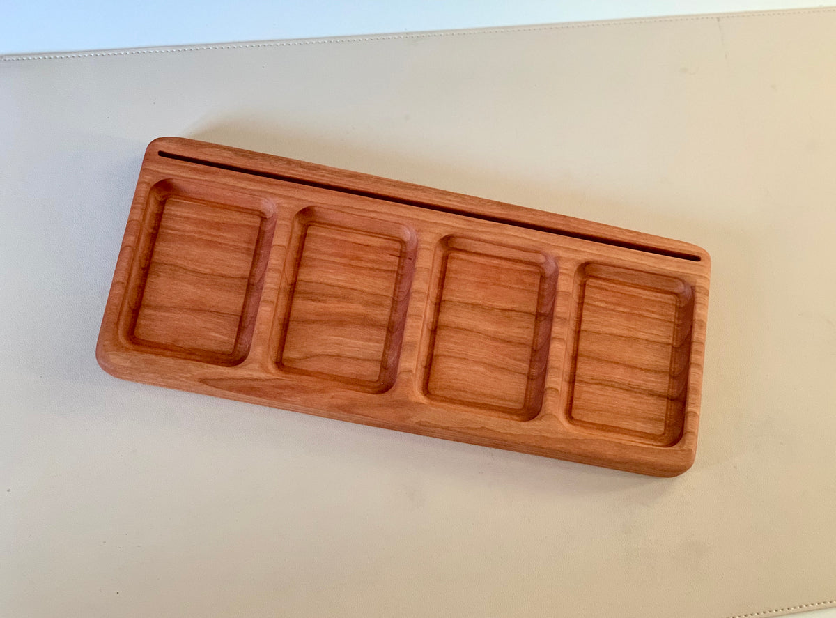 Rectangular wooden tray with four compartments and a narrow slot at the top on a light surface