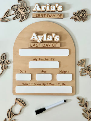 Wooden dry erase first and last day of school sign with white acrylic name pieces and black dry erase marker surrounded by wood flowers