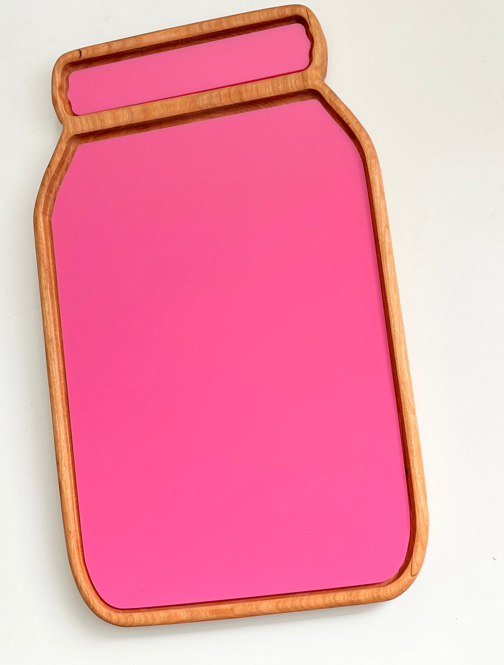 Wooden tray shaped like a jar with a bright pink base and smooth natural wood frame on white background