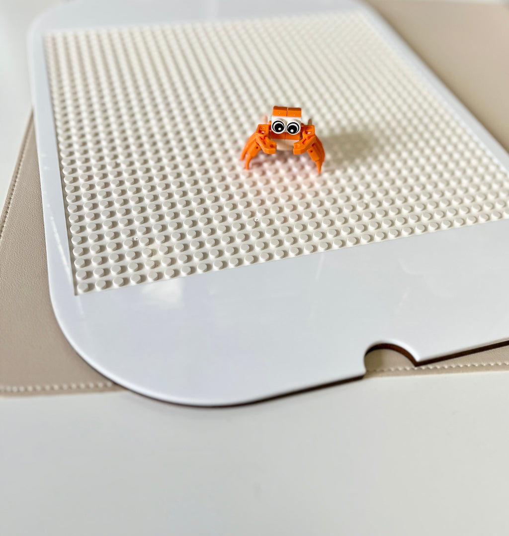 White acrylic Flisat table top insert with Lego studs and small orange buildable figurine on beige surface