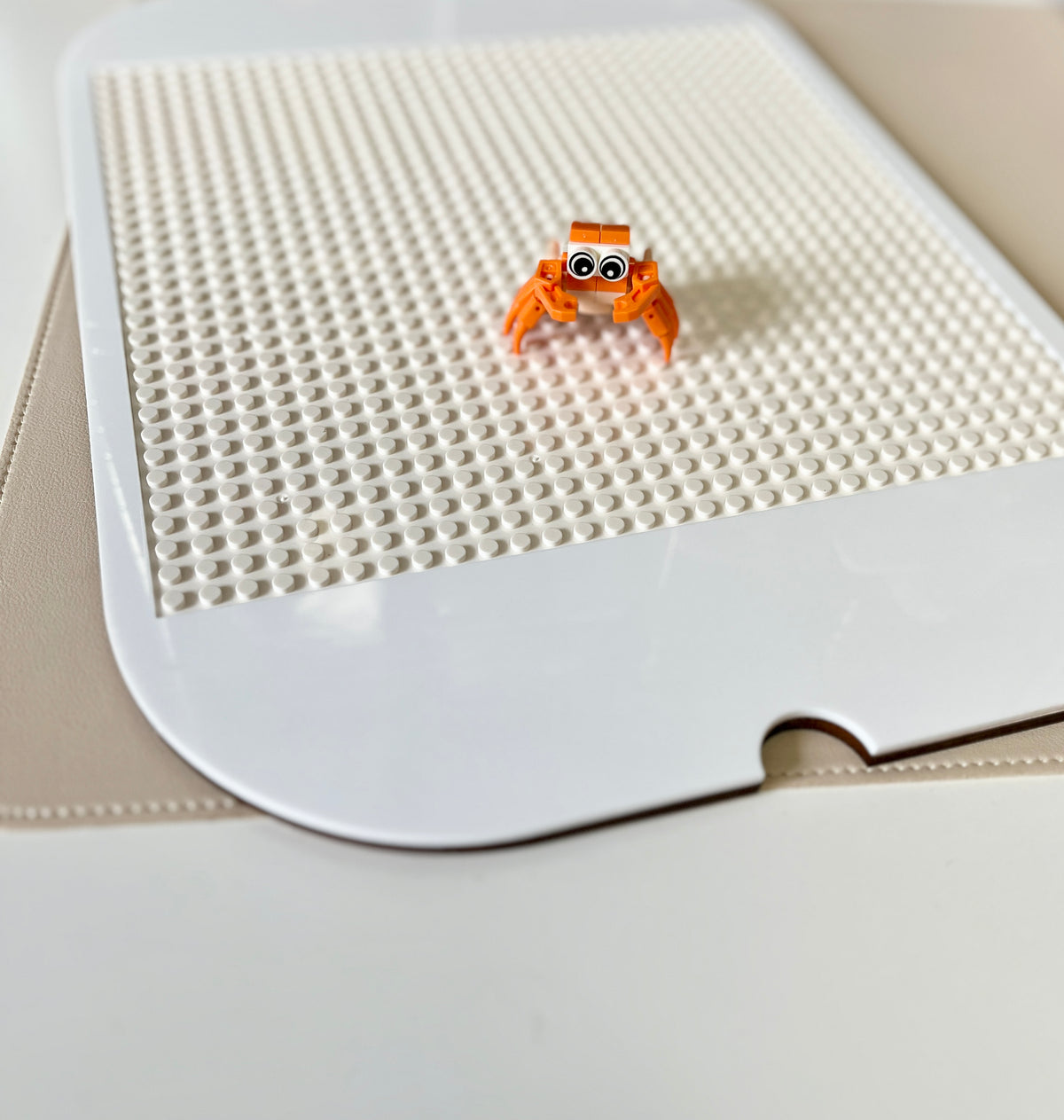 White acrylic Flisat table top insert with Lego studs and small orange buildable figurine on beige surface