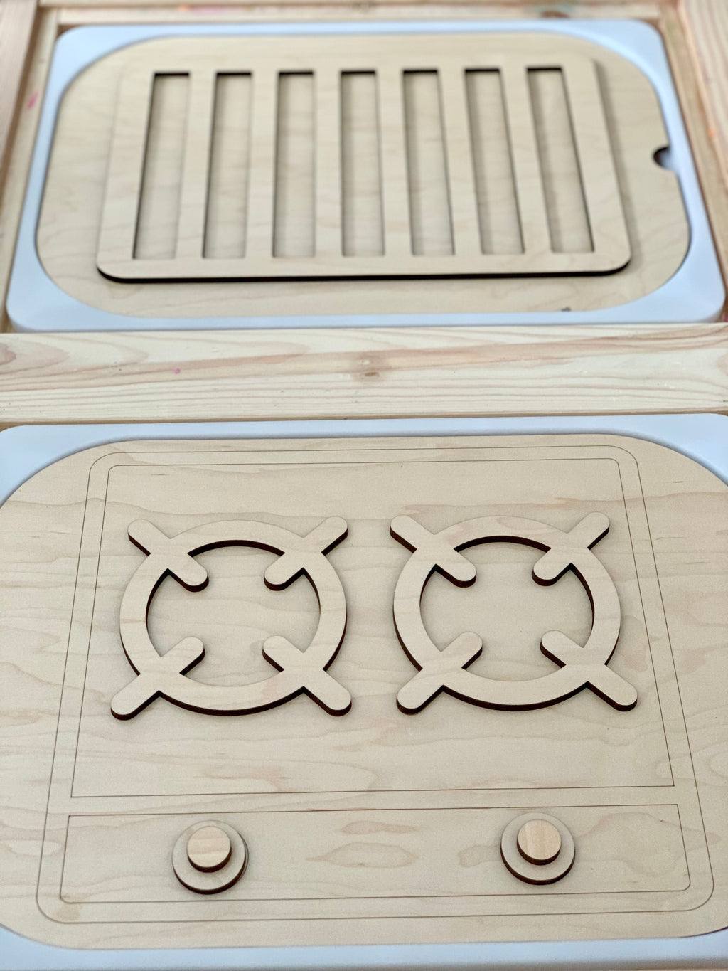 Wooden stove top and oven insert with turnable knobs and burner designs on maple plywood surface