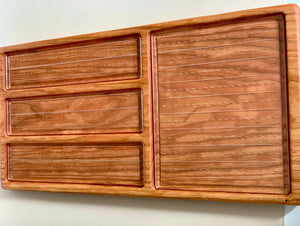 Wooden organizer tray with three long narrow compartments and one large square section on a light surface