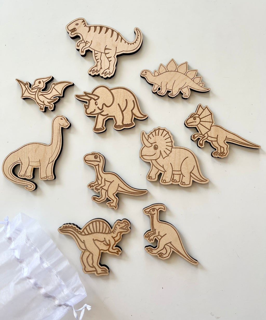 Ten wooden dinosaur figures including T-Rex, Triceratops, Stegosaurus, and Pterodactyl on a white surface