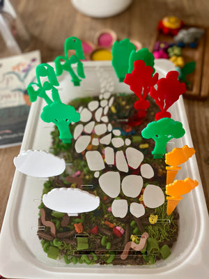 White tray with a detailed nature-inspired base, holding colorful translucent acrylic pegs shaped like trees, clouds, and plants, featuring STEM Insert – Acrylic Insert with Different Peg Options - Neighborhood, Veggie Garden, Flower Garden, Under the Sea + More, handcrafted, homeschool, education resources.