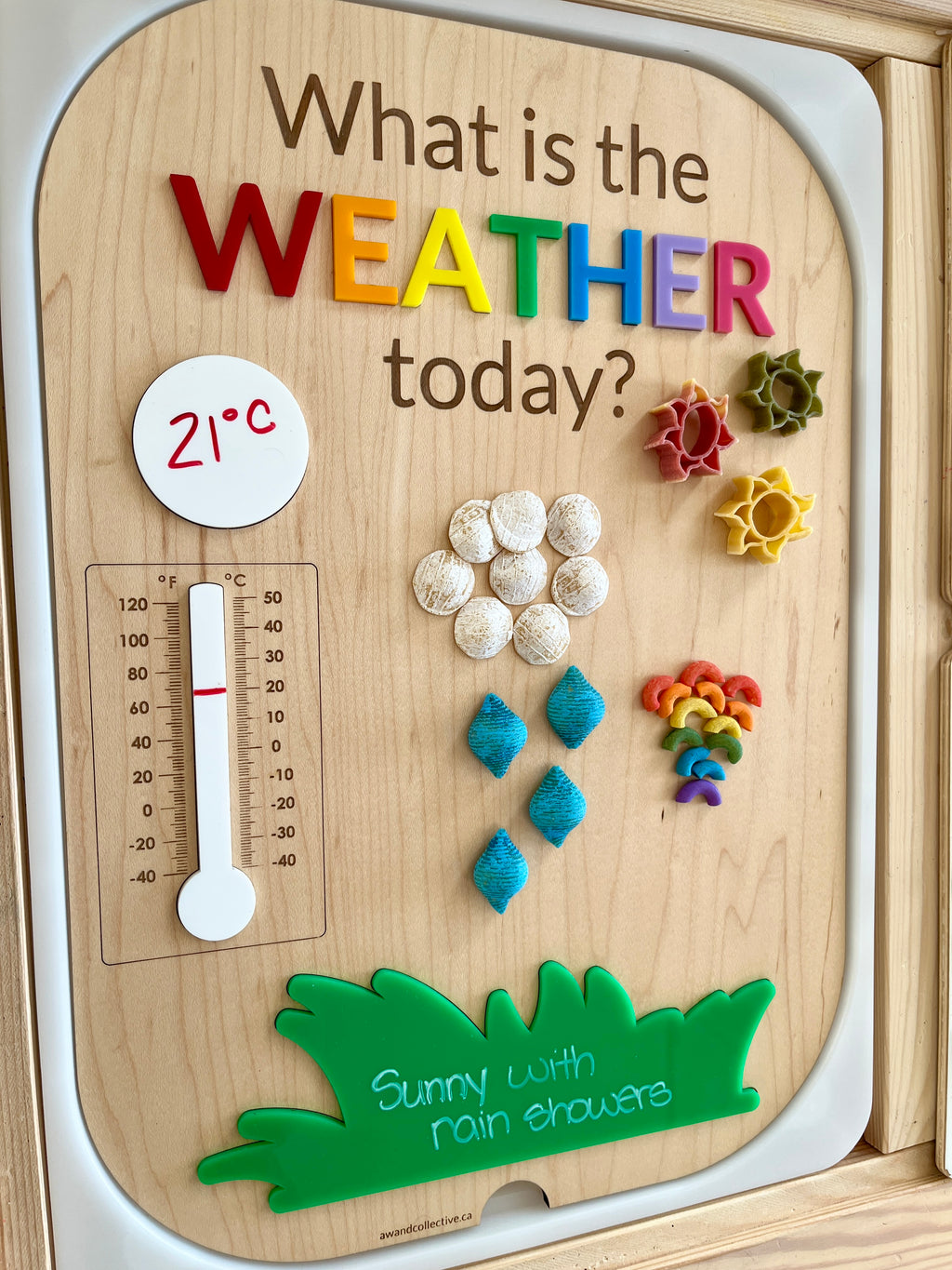 Wooden weather learning board with colorful letters, pasta shapes for sun, clouds, rainbows, and a 21°C thermometer reading