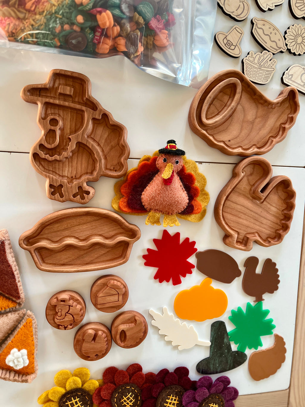 Wooden Thanksgiving-themed trays shaped like a turkey, cornucopia, pie, and mitten with felt turkey and colorful seasonal cutouts on white surface