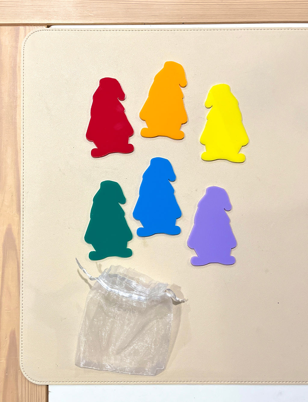 Set of six colorful gnome-shaped dry erase boards with a small white drawstring pouch on beige mat