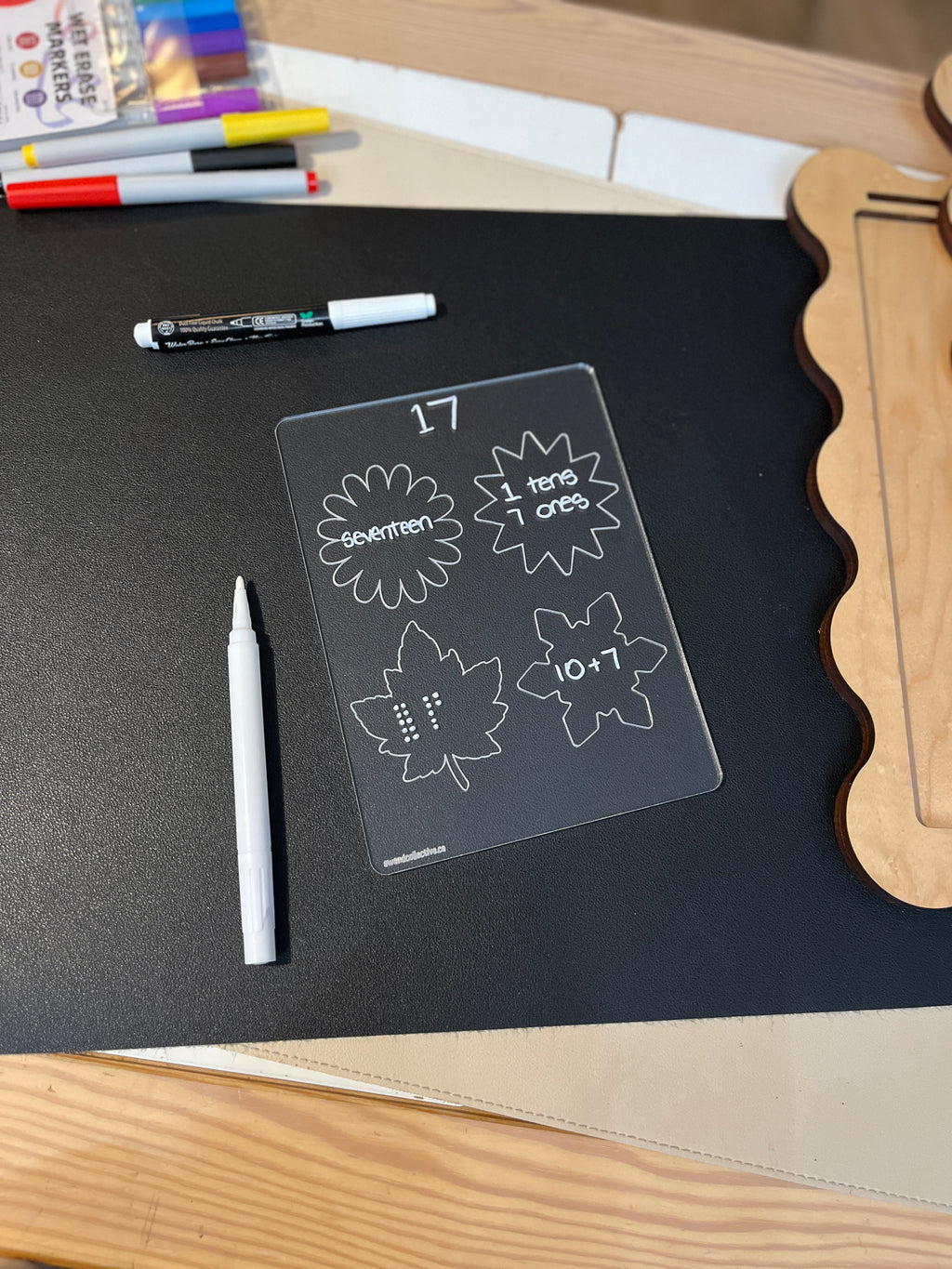 Clear learning board with the number 17 shown as word, tens and ones, dots, and equation on black surface