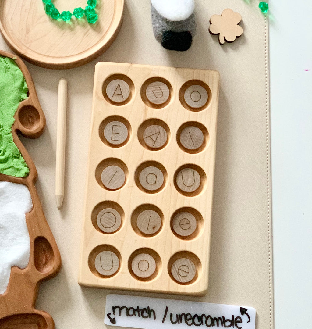 Light wooden board with circular slots holding pieces engraved with letters on a white table surface