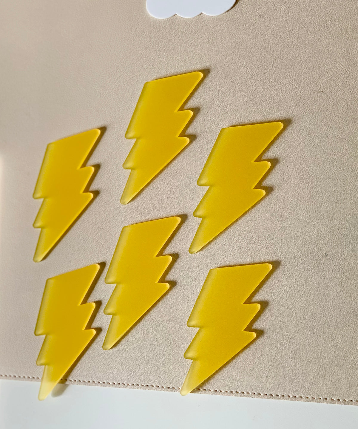 Seven bright yellow lightning bolt shapes arranged on a light beige textured surface