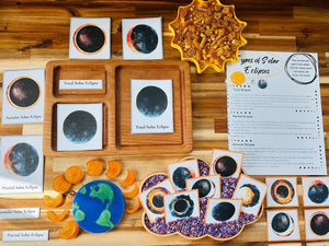 Educational solar eclipse learning materials with labeled wooden trays and celestial model on wood table