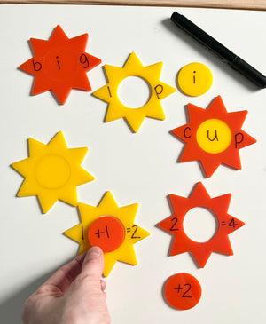 Little Dry Erasables - Sunshines 2 Part featuring colorful yellow and orange star-shaped pieces used to form words and simple math equations with a black dry-erase marker, handcrafted homeschool education resources.
