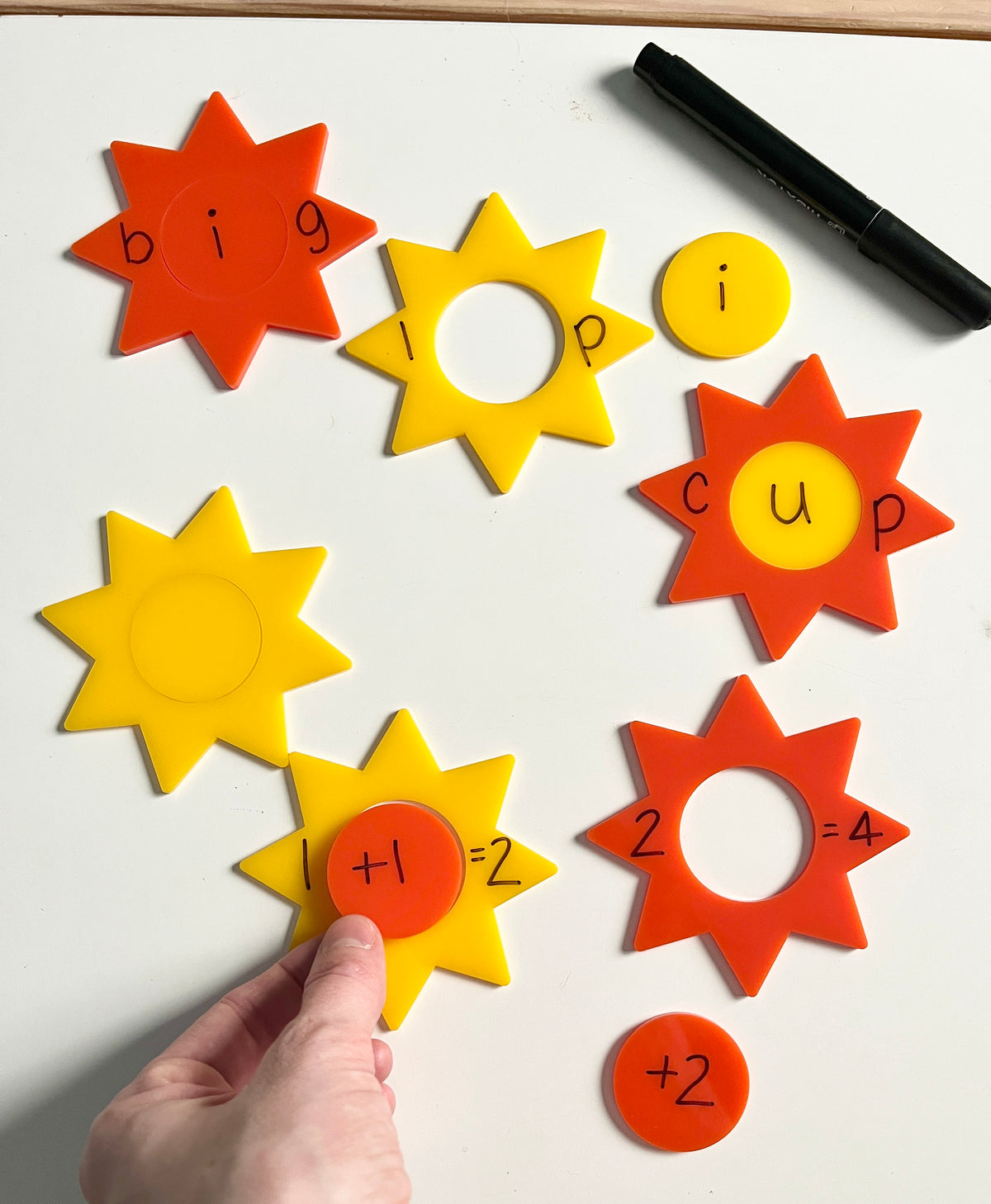 Little Dry Erasables - Sunshines 2 Part featuring colorful yellow and orange star-shaped pieces used to form words and simple math equations with a black dry-erase marker, handcrafted homeschool education resources.