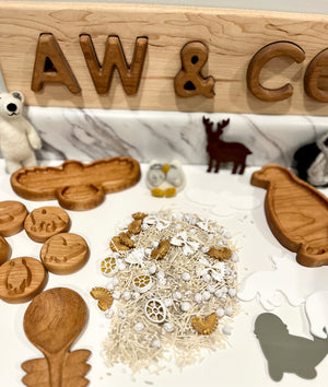 Wooden animal-shaped tokens including bird, moose, and others with small white natural decorations on marble surface