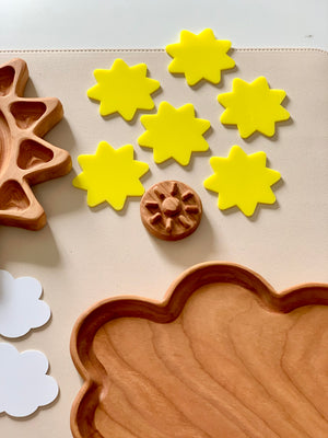 Set of six bright yellow wooden sun shapes with wooden cloud tray and natural wooden gear on beige background
