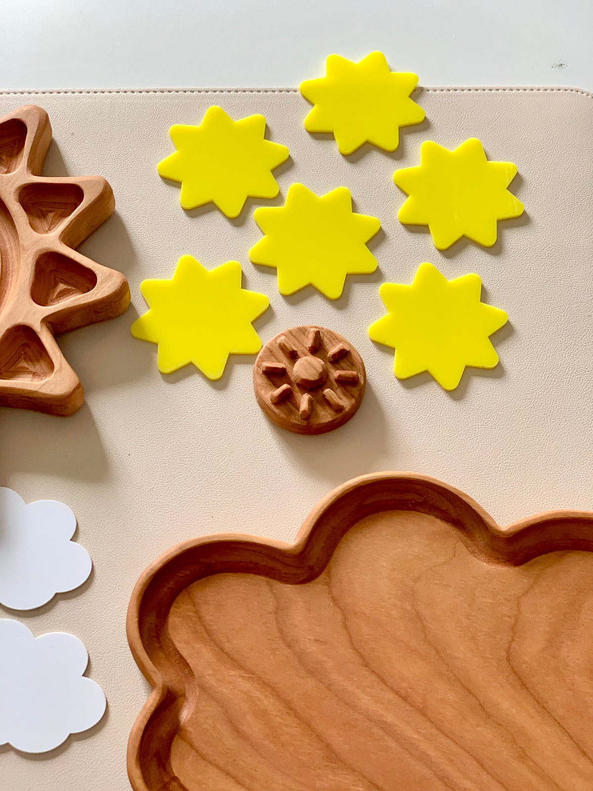 Set of six bright yellow wooden sun shapes with wooden cloud tray and natural wooden gear on beige background