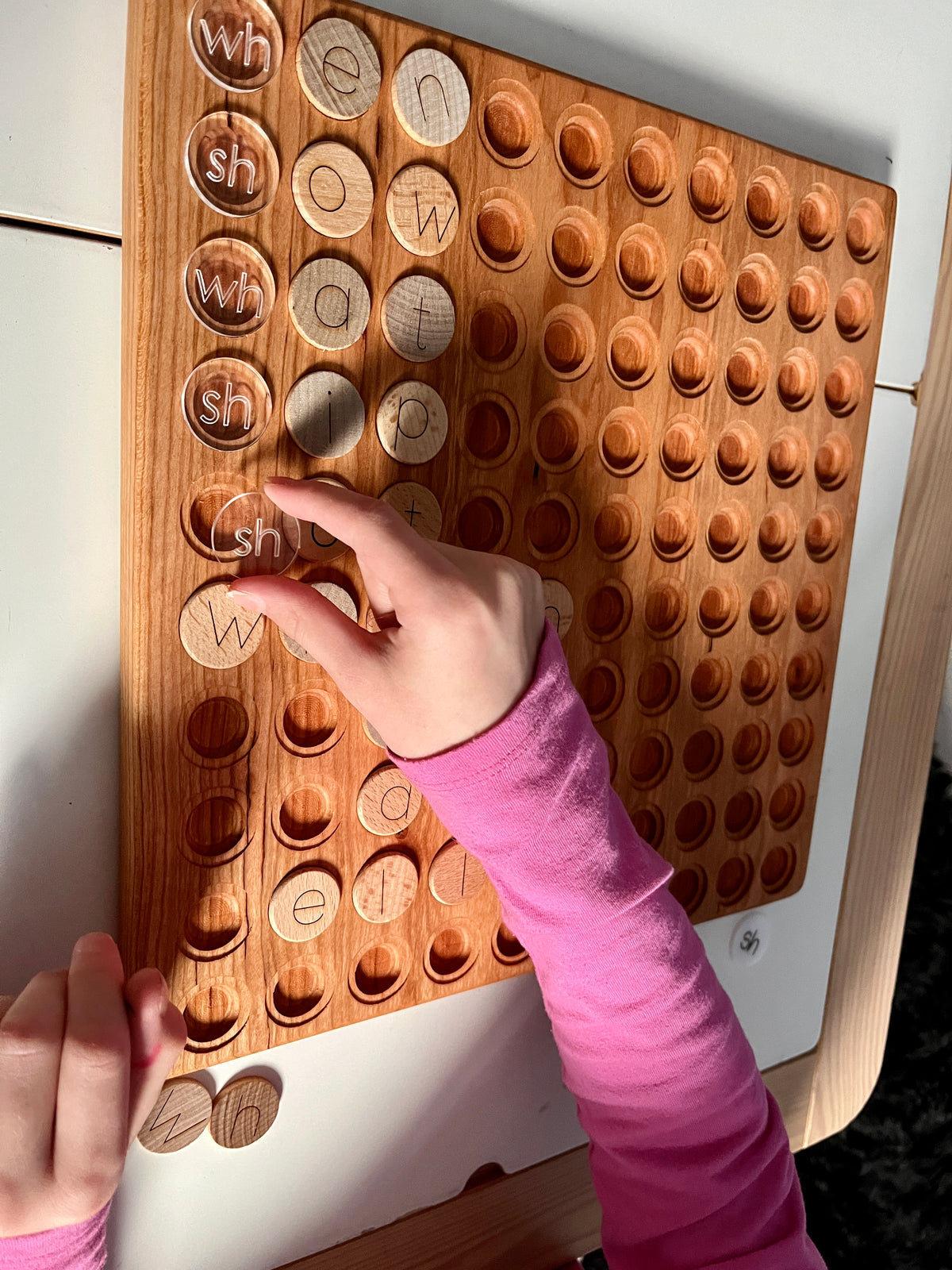Wooden 100 Hundred Board Tray | Counting & Number Sense Learning Tray | Combos Available showing a child’s hands placing letter tokens on a handcrafted wood board with round indentations, unique homeschool educational resources.