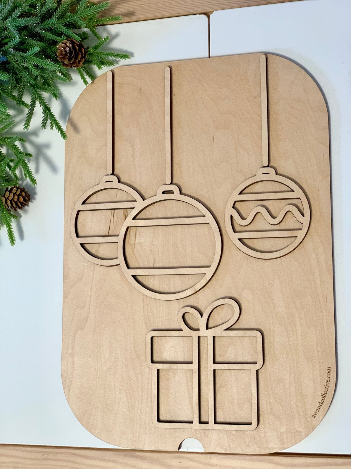 Maple plywood Flisat table top insert with cutouts of hanging Christmas ornaments and a gift box on white surface