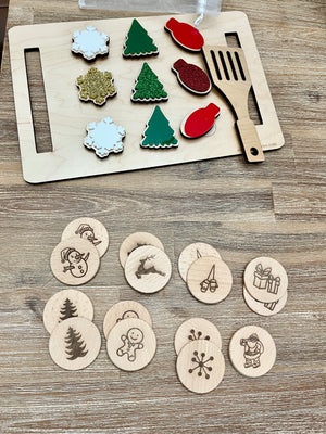 Wooden Christmas memory game pieces including painted snowflakes, trees, ornaments, and engraved holiday icons on wood background