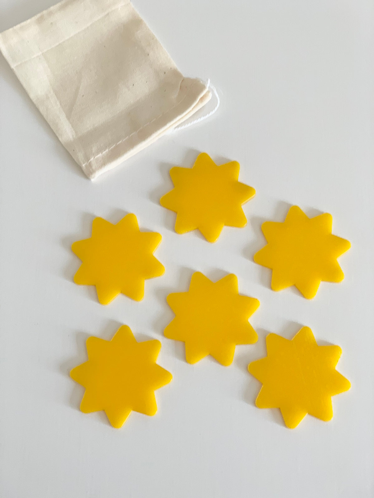 Set of six yellow sun-shaped dry erase pieces with soft drawstring cotton storage bag on white background
