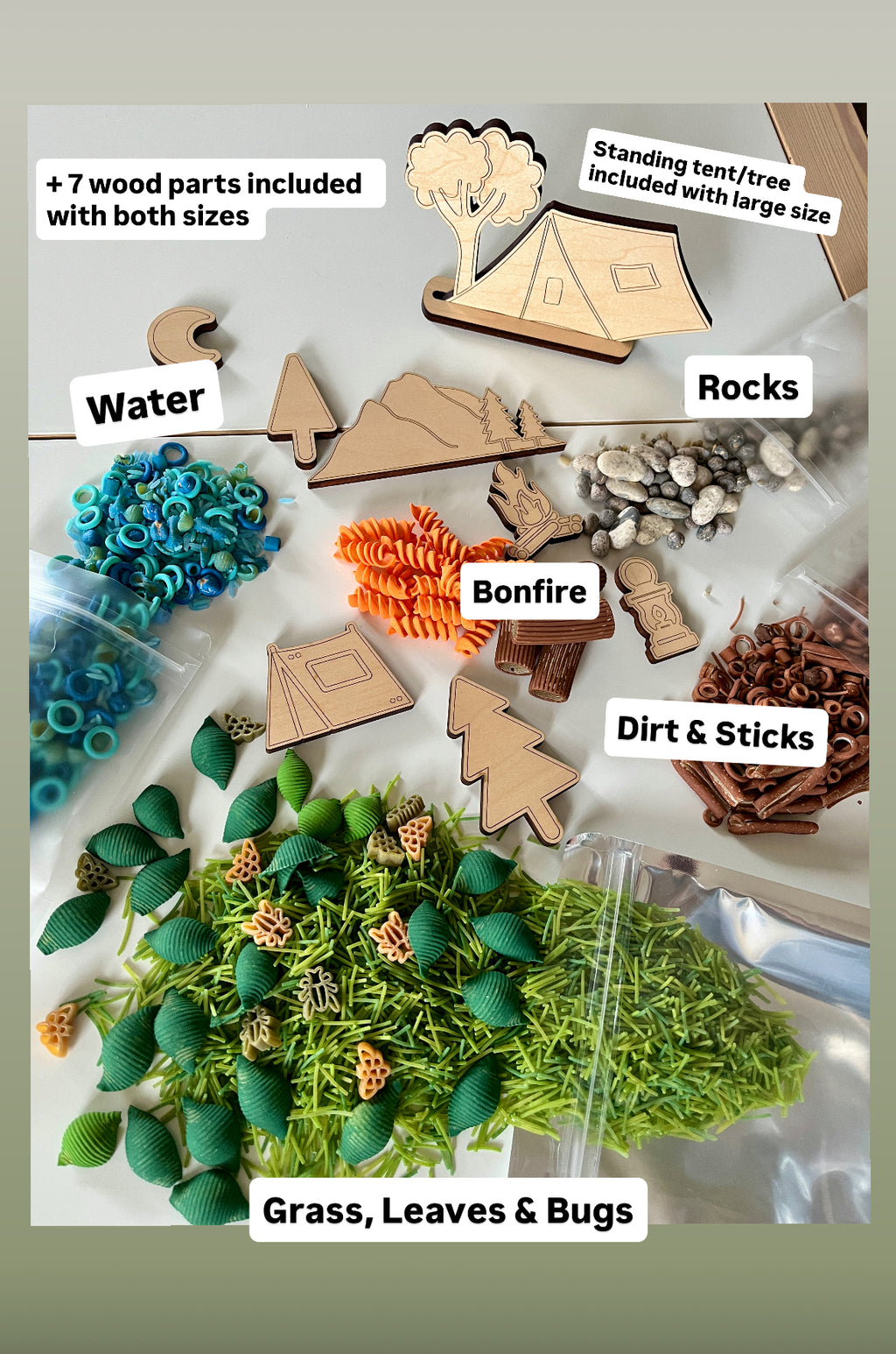 Wooden camping shapes and nature-themed sensory play items including blue rings, orange spirals, green leaves, and small rocks on white surface