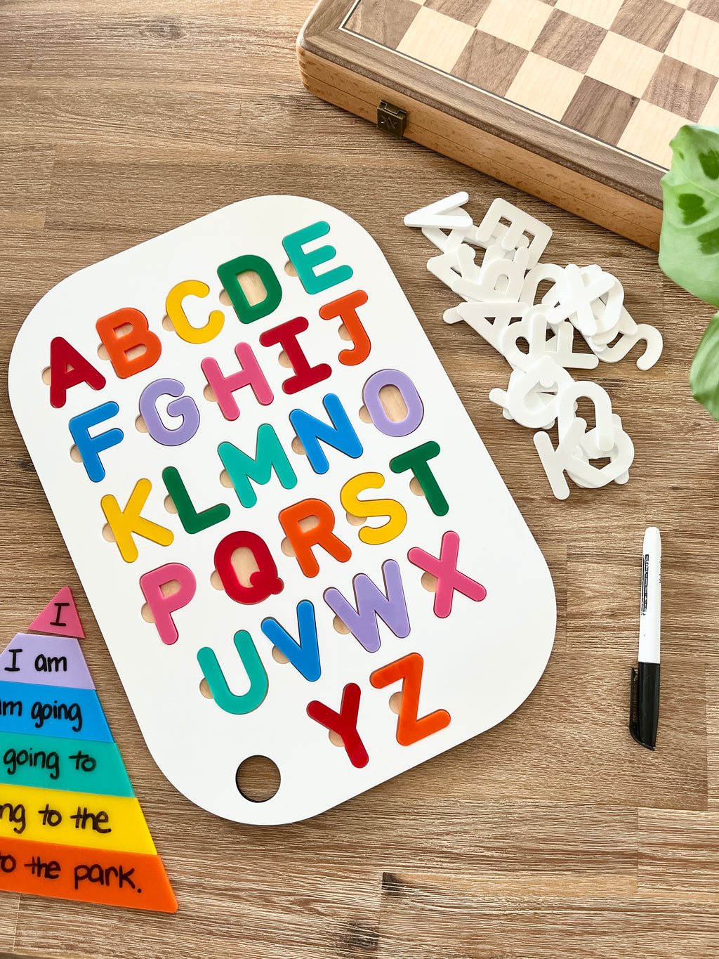 Acrylic Dry Erase Uppercase Alphabet Puzzle Flisat Table Top Insert with Both Rainbow and White Letters showing colorful uppercase letters on white insert, black marker, wood grain surface, handcrafted homeschool education resources.