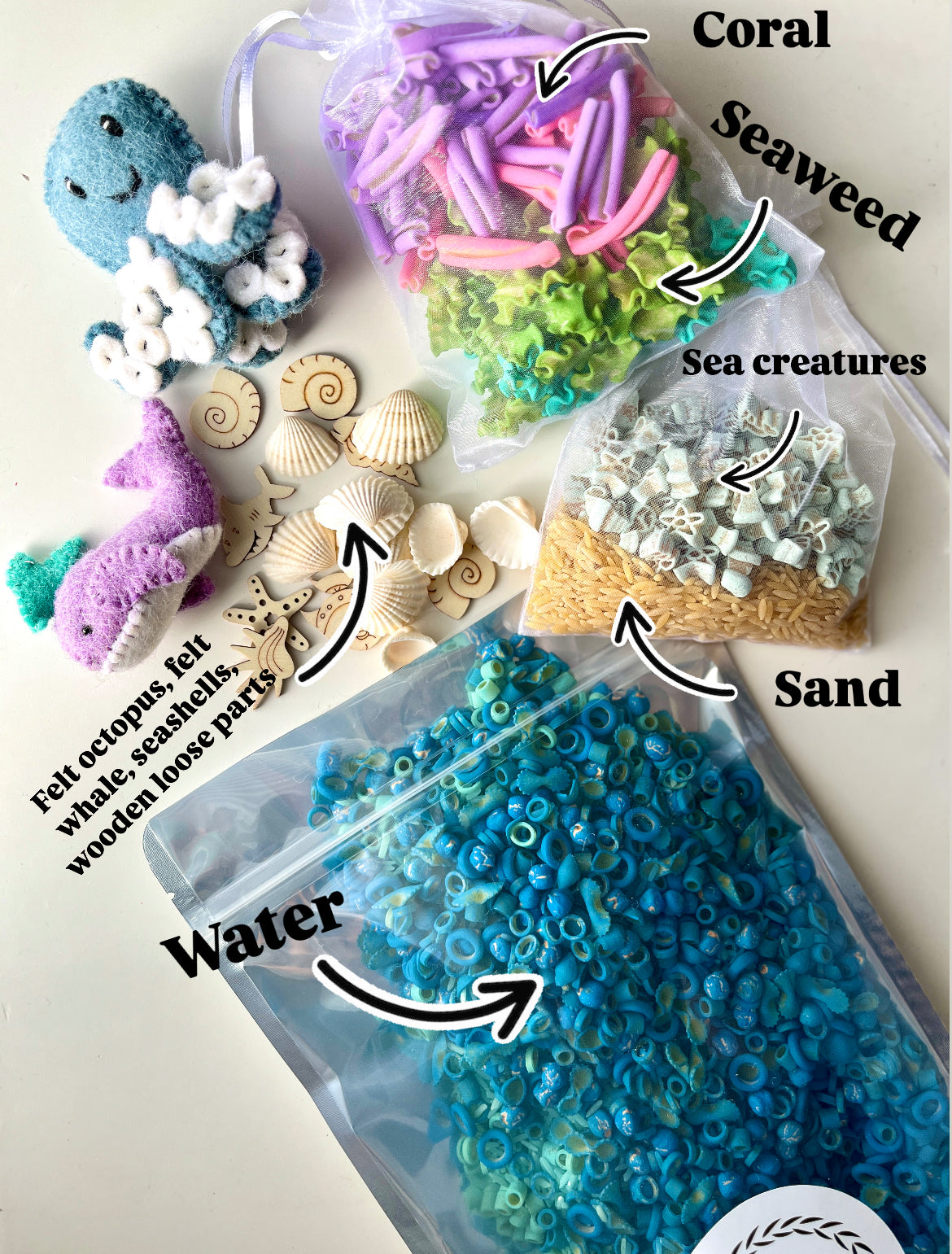 Play set with felt sea animals, wooden seashells, yarn coral and seaweed, small sea creature shapes, wooden beads, and dry pasta.