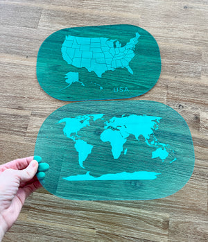 Hand holding two translucent blue dry erase acrylic tracing boards featuring maps of the USA and world, showcasing Translucent Blue Maps (USA, World, Canada) Dry Erase Acrylic Tracing Board; also fits as a Flisat Insert with handcrafted, homeschool, education resources.