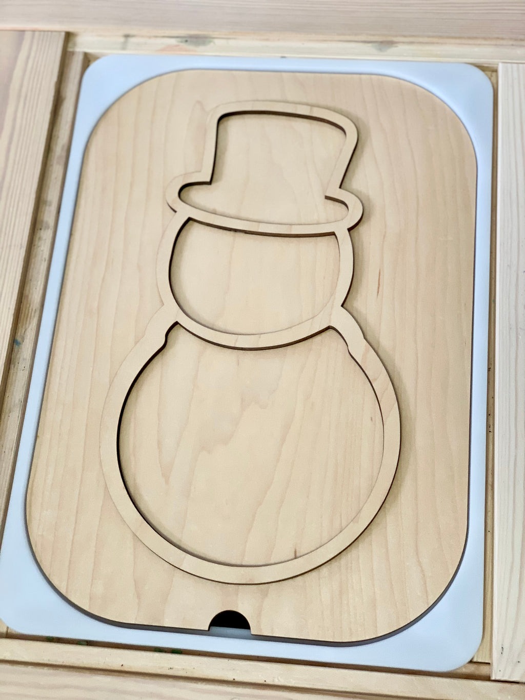 Light natural wood insert shaped like a snowman with a top hat outline and smooth edges in a white frame
