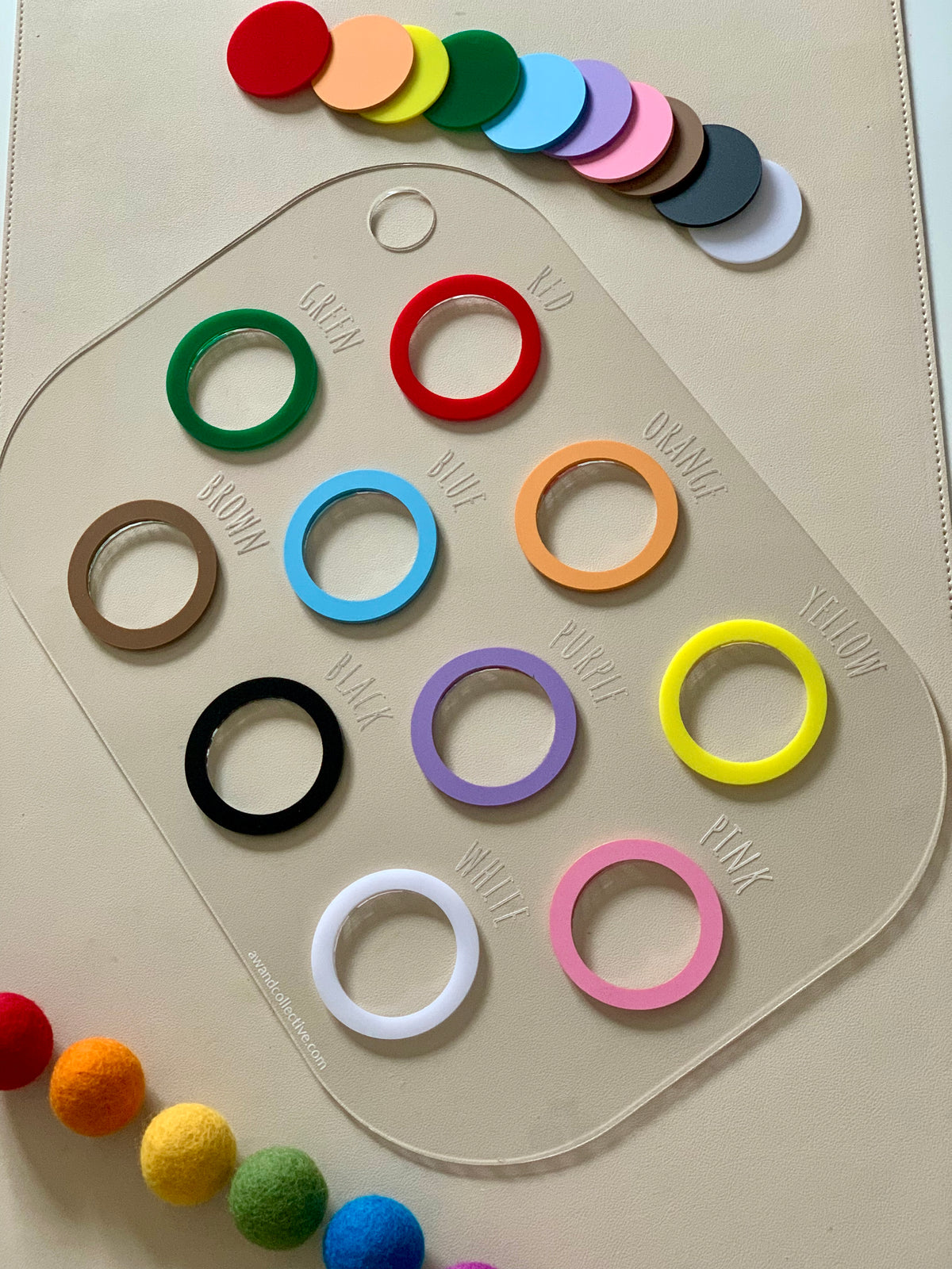 Clear rectangular colour sorting Flisat table bin lid with twelve coloured rings and matching felt balls on beige background