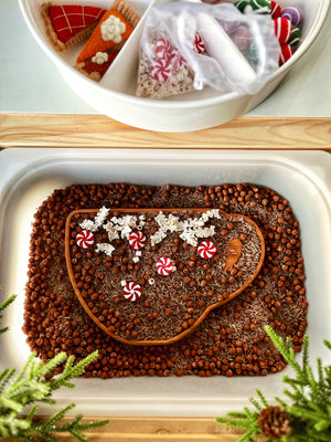 Tray filled with hazelnuts and rice shaped like a cup with popcorn, peppermint candies, and pine greenery nearby