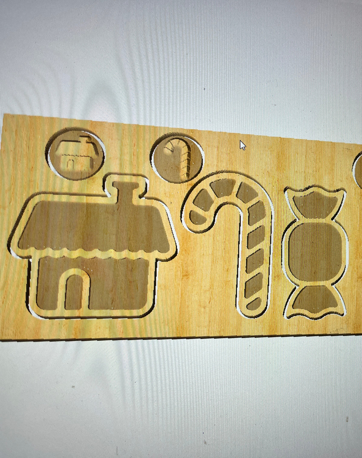 Wooden puzzle board featuring cutouts of a house, candy cane, wrapped candy, and two round shapes on a white background