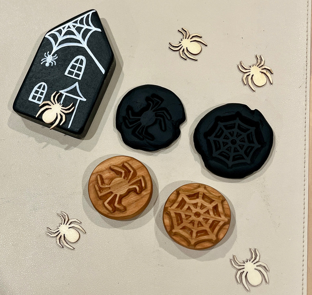 Black house with white spiderweb art, black and wooden tokens carved with spiders and webs, and small wooden spider cutouts