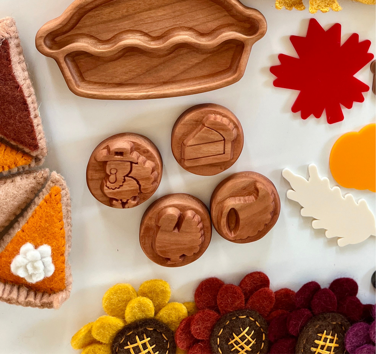 Carved wooden pie-shaped tray with circular wooden tokens featuring Thanksgiving-themed icons on white surface
