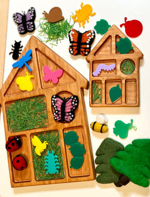 Wooden house shaped tray with compartments, with nature-themed felt and acrylic pieces including leaves, butterflies, and a bee on a light background.