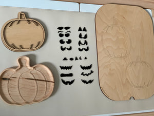 Laser cut wooden pumpkin plate and tray with various interchangeable jack-o-lantern face pieces on light surface