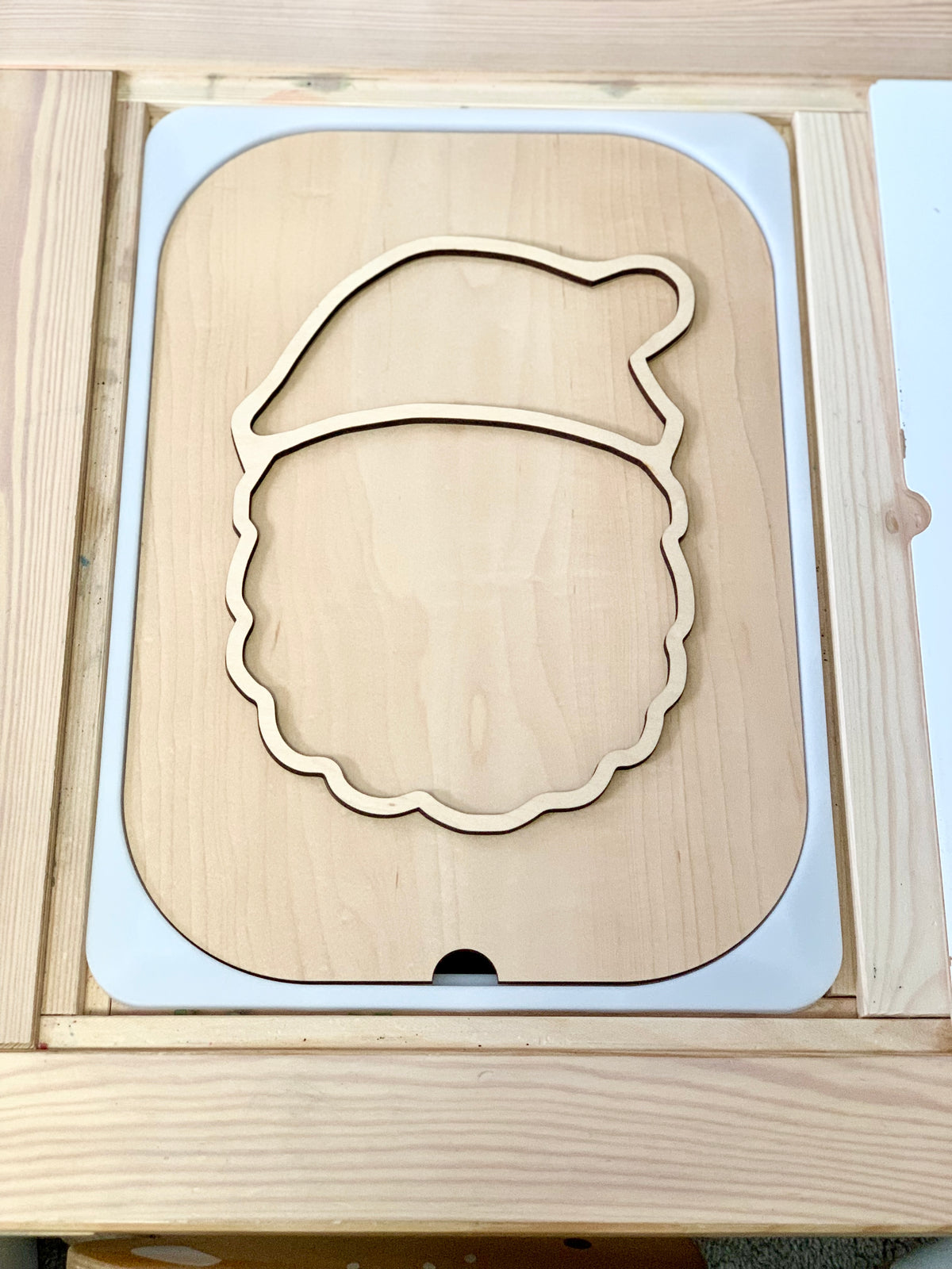 Light wood puzzle outline shaped like a Santa Claus head with a hat on a matching wooden base