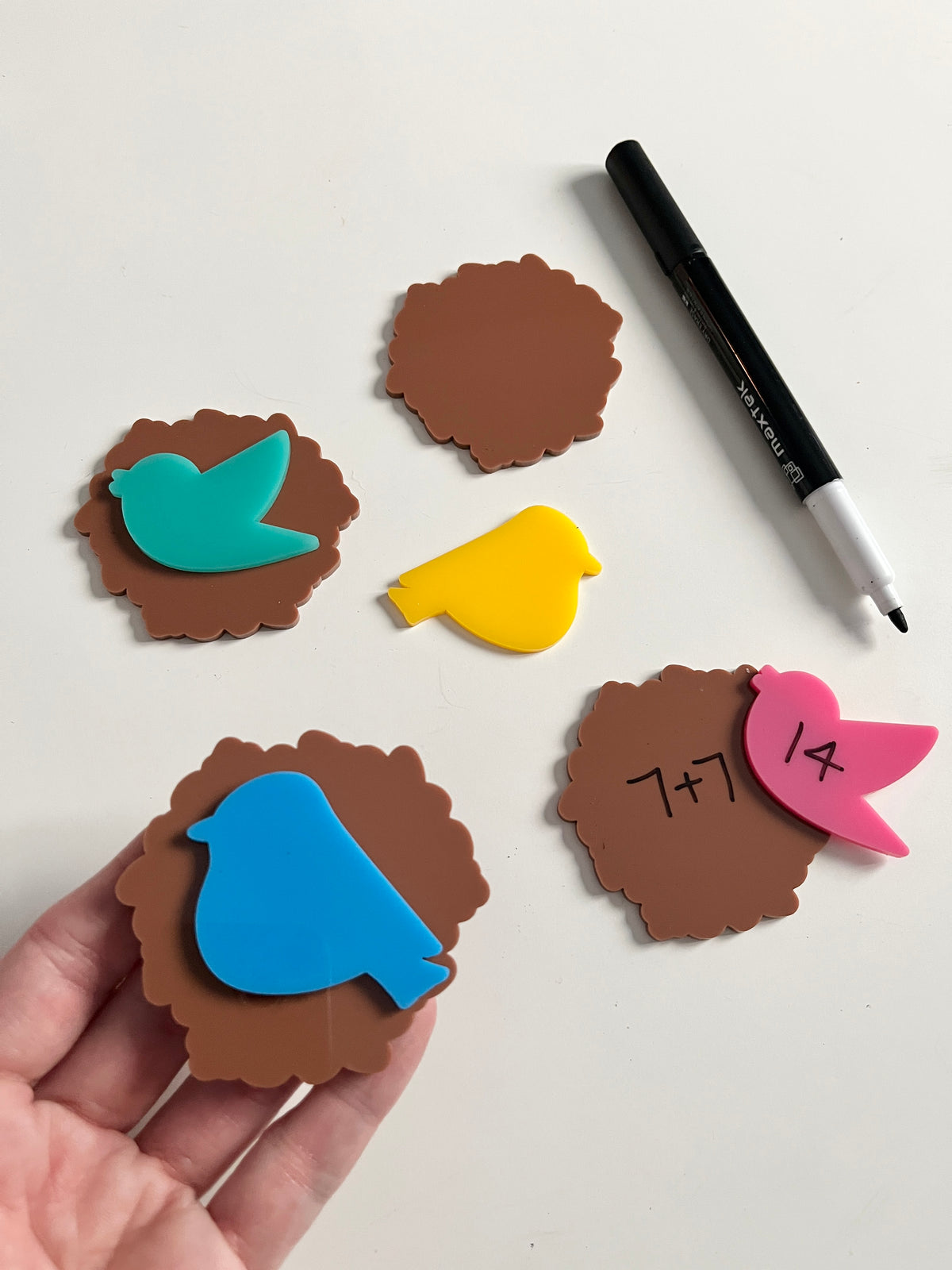 Little Dry Erasables - Birds & Nests showing colorful bird-shaped pieces in blue, pink, yellow, and green paired with brown nest shapes, handwritten math practice, black dry-erase marker, handcrafted homeschool education resources.
