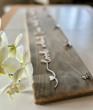 Wooden art display sign with white cursive lettering and heart detail, natural wood grain background with clip holders on white table