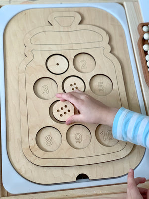 Wooden jar-shaped Flisat table insert with number-labeled cookie slots and child placing a wooden cookie piece