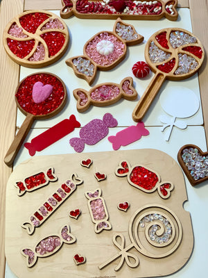Wooden trays and shaped cutouts filled with red, pink, and clear acrylic beads arranged on a light surface
