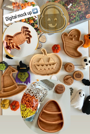 Halloween-themed wooden trays shaped like pumpkin, ghost, candy corn, witch hat, and crab surrounded by autumn decor and craft supplies