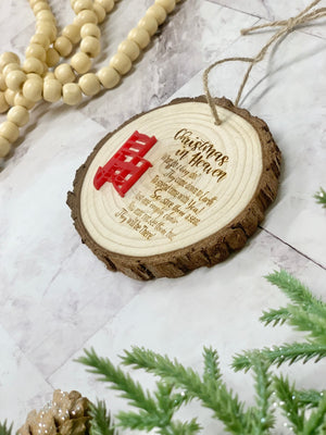 Wood slice memorial poem Christmas ornament with red chair decoration on marble surface with beads and greenery nearby