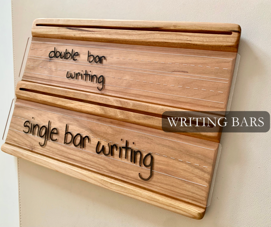 Wooden writing practice board with engraved single and double bar guidelines mounted on a light wall