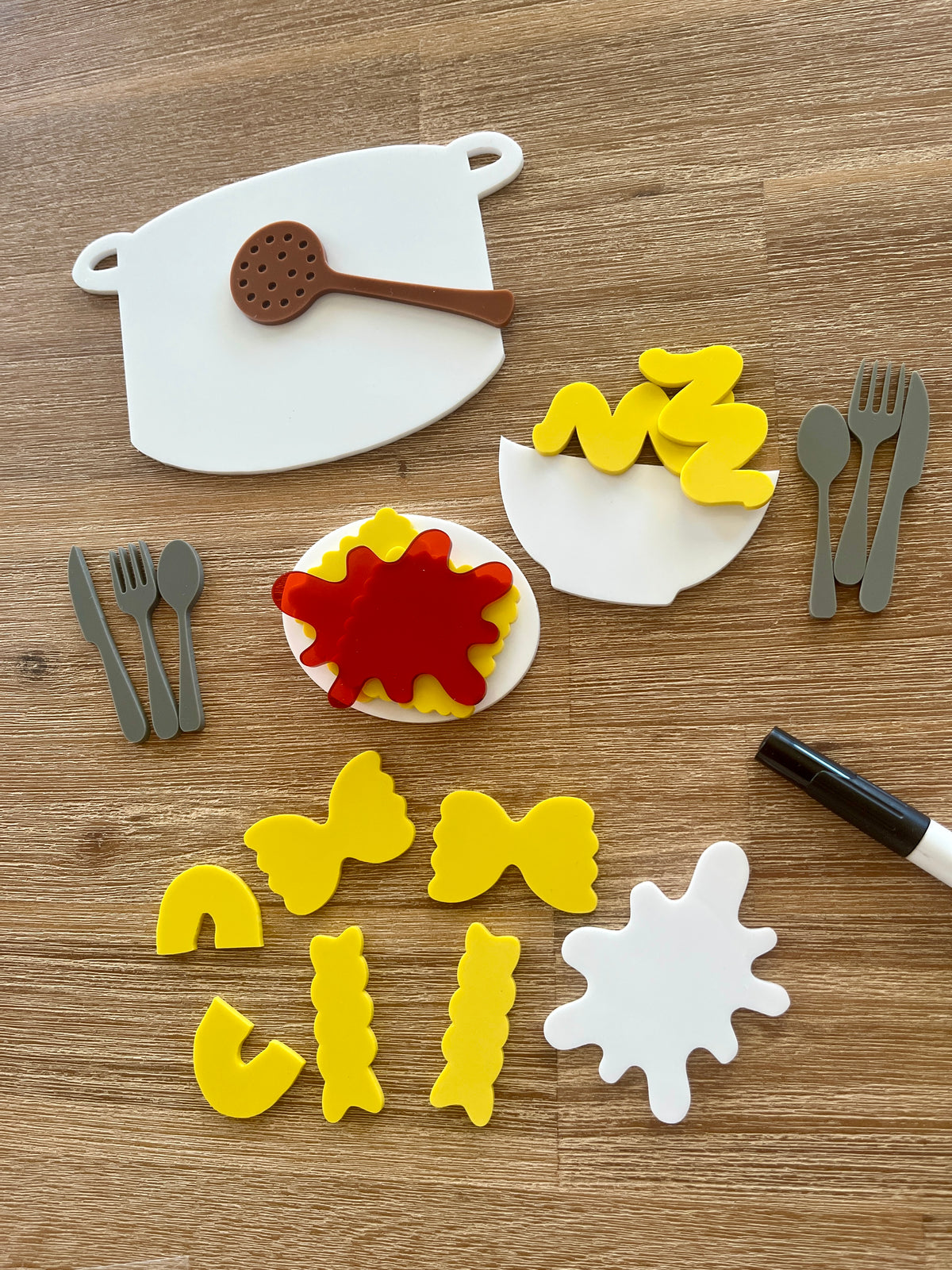 Little Dry Erasables - Pasta with Sauce, Pot, Plate, Bowl and Cutlery featuring handcrafted wooden shapes of pasta varieties, sauce splatters, cooking pot, utensils, and a black dry erase marker for homeschool education resources.