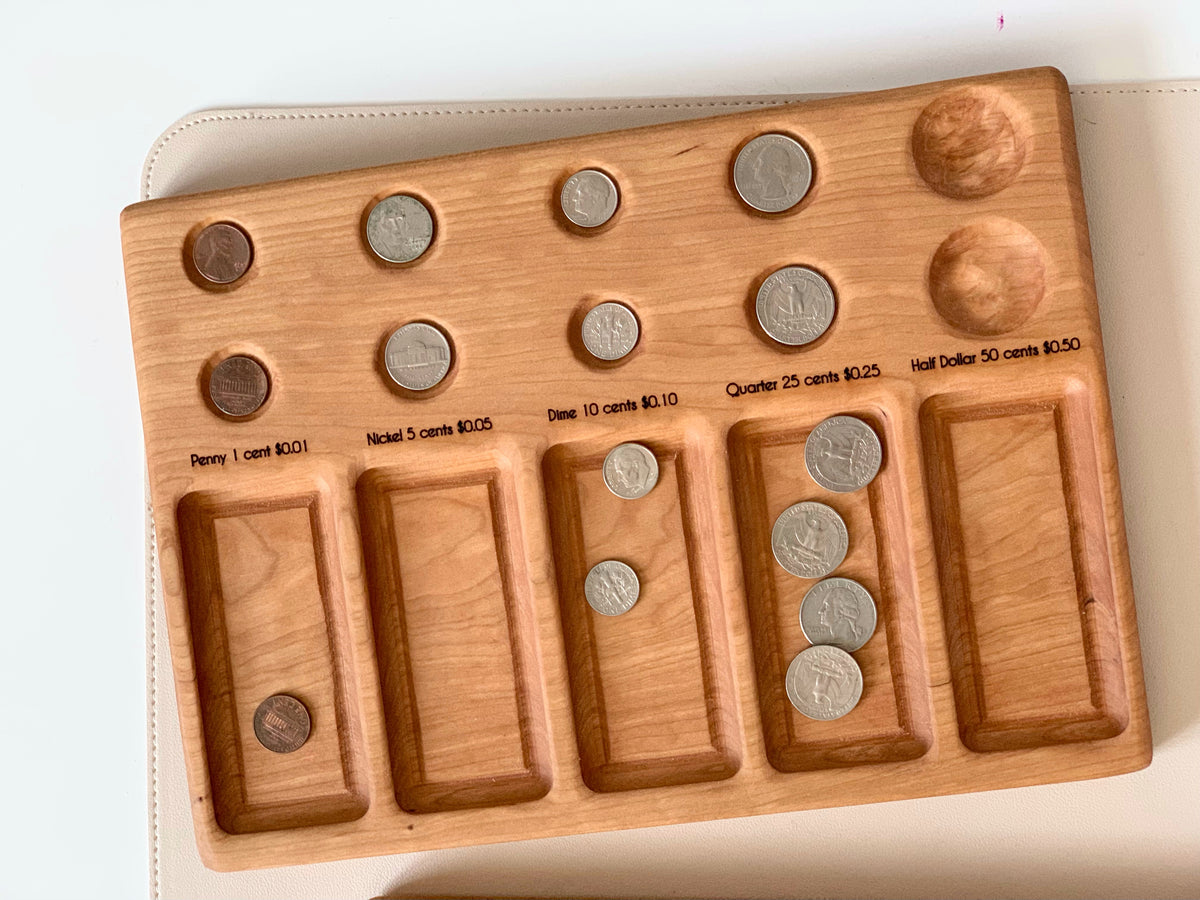 Wooden coin sorting board with labeled sections holding US coins including pennies, nickels, dimes, quarters, and half dollars